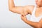 Woman pulling excess fat on her under arm, problem armpit skin, studio isolated