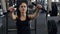 Woman pumping chest muscles on special equipment in sport gym