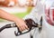 Woman pumping gasoline fuel in car at gas station.