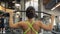 Woman pumps iron in Fitness-station. View from her back.