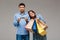 Woman with purchases, man holding last money over grey background.