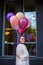 Woman with purple hair standing turn her right outdoor with baloons