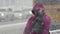Woman in purple jacket walks sidewalk during snowfall, Pacific snow cyclone
