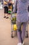 Woman in purple pants waiting in line at nursery with bags of soil and flowers in shopping cart - rear view - cropped - with other