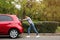 Woman pushing broken car on the road