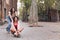 woman pushing her friend sitting on a skateboard