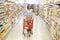 Woman pushing trolley along supermarket aisle