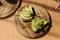 Woman put mustard seedlings on avocado sandwich with dark rye bread made with fresh sliced avocados from above with