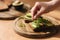 Woman put mustard seedlings on avocado sandwich with dark rye toasted bread made with fresh sliced avocados from above