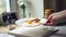 Woman put plate with fried eggs and slices of toast bread on kitchen table