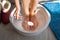 Woman put spoon of baking soda in bath with hot water for his feet. Homemade bath soak for dry feet skin.