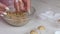 A woman puts balls of peanut butter, chocolate and coconut flour into paper tartlets. Prepares healthy sweets. Close-up shot