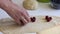 A woman puts cherries on the rolled dough. Cooking dumplings