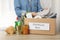 Woman puts clothes donation box on wooden table