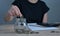 A woman puts a coin in a jar on a wooden table to save money And record household income on the tablet