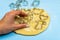 A woman puts cookie cutters on thinly rolled dough on a blue background
