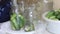 A woman puts cucumbers in pickling jars. There are cucumbers nearby in a basin. Harvest conservation. Close-up shot