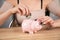 a woman puts a dollar bill in a piggy bank