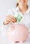 Woman puts euro cash into large piggy bank