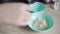 Woman puts fresh steamed white rice into deep blue plate with spoon. The grains of porridge are crumbly and they are