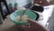 Woman puts fresh steamed white rice into deep blue plate with spoon. The grains of porridge are crumbly and they are