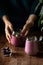 A woman puts a glass of blueberry smoothie on the table