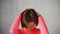 Woman puts hands on back of head and tilts head forward stretching neck muscles.