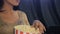 Woman puts her fingers on popcorn at the movie theater