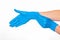 Woman puts on her hand a nitrile blue glove with her other hand on a white background