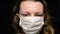 Woman puts on medical mask on black background