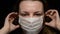 Woman puts on medical mask on black background