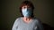 Woman puts on a medical mask on a dark background and then removes it