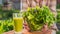A woman puts a plate of lettuce leaves around a glass of green smoothie. Vitamin drink