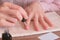 Woman puts primer on her nails before putting shellac. Close-up hands.