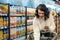 a woman puts a product with a list of products on the phone into a cart in the supermarket