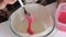 A woman puts a spoonful of dough in a glass baking dish. To make a cake.