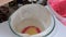 A woman puts a spoonful of dough in a glass baking dish. To make a cake.