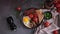 woman puts tasty dish breakfast onto dark background - fried bacon, eggs, mushrooms and tomatoes in ceramic pot