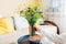 Woman puts vase with blue and yellow flowers on table. Taking care of coziness at home. Interior with Ukrainian colors