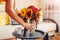 Woman puts vase with sunflowers and zinnia flowers on table. Housewife takes care of interior and fall decor at home.