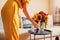 Woman puts vase with sunflowers and zinnia flowers on table. Housewife takes care of interior and fall decor at home.