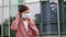 Woman puts white medical mask on background of office building.