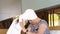 A woman puts a white towel on her head with wet hair sitting on a bed at home.