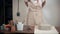 Woman is putting on an apron in her handicraft workshop, standing near table,