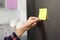 Woman putting blank sticky note on refrigerator door