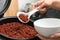 Woman putting brown rice into bowl from multi cooker in kitchen