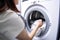 Woman putting clothes into washing machine in laundry, closeup. Generative AI