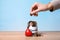 Woman putting coin into jar with label DONATE on table against color background, closeup.