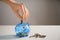 Woman putting coin into piggy bank and keys on table. Concept of saving money for buying new house