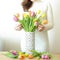 Woman putting colorful tulips in vase.